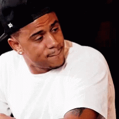 A Man Wearing A Hat And A White Shirt Is Making A Funny Face GIF