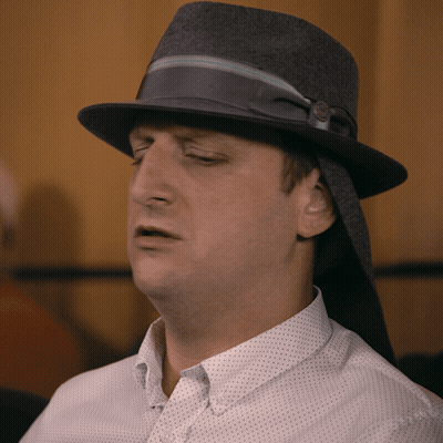 A Man Wearing A Hat And A White Shirt Looks Tired GIF