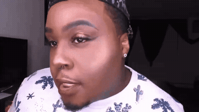 A Man Wearing A Hat And A White Shirt With Cactus On It Looks At The Camera GIF