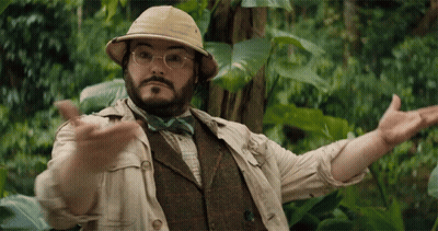 A Man Wearing A Hat And Bow Tie Is Standing In The Jungle GIF
