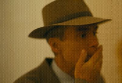 A Man Wearing A Hat And Covering His Mouth GIF