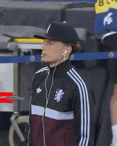 A Man Wearing A Hat And Earbuds Is Wearing An Adidas Jacket GIF