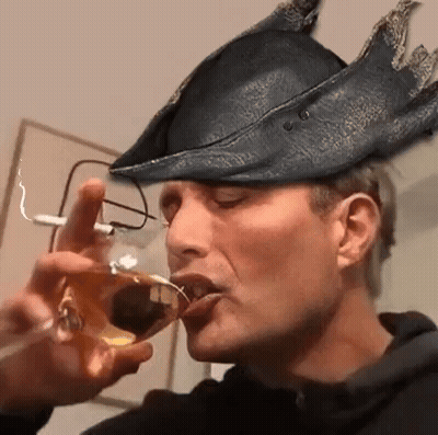 A Man Wearing A Hat And Glasses Is Drinking From A Wine Glass . GIF