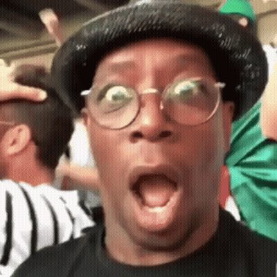 A Man Wearing A Hat And Glasses Is Making A Surprised Face . GIF