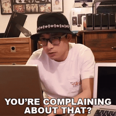 A Man Wearing A Hat And Glasses Is Sitting In Front Of A Laptop And Says You 'Re Complaining About That ? GIF