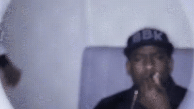 A Man Wearing A Hat And Glasses Is Smoking A Cigarette . GIF