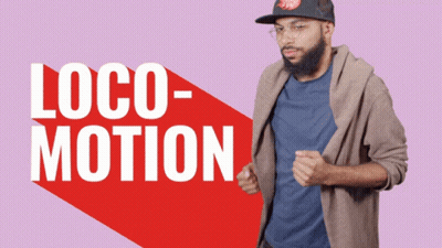 A Man Wearing A Hat And Glasses Is Standing In Front Of A Sign That Says Loco Motion GIF