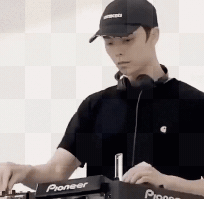 A Man Wearing A Hat And Headphones Is Playing Music On A Dj Machine . GIF