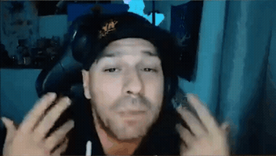 A Man Wearing A Hat And Headphones Is Sitting In A Chair And Making A Funny Face . GIF