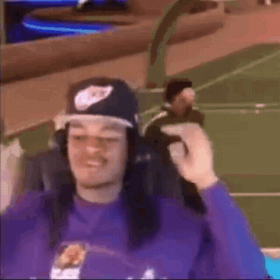A Man Wearing A Hat And Headphones Is Sitting In A Chair On A Basketball Court . GIF