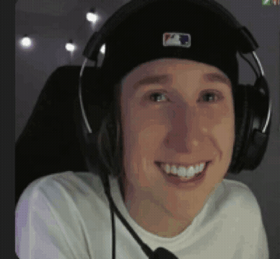 A Man Wearing A Hat And Headphones Is Smiling . GIF