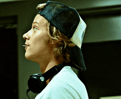 A Man Wearing A Hat And Headphones Looks To His Right GIF