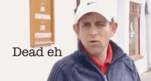 A Man Wearing A Hat And Jacket Is Standing In Front Of A Building With The Words `` Dead Eh '' Written On It . GIF