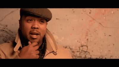 A Man Wearing A Hat And Scarf Is Standing In Front Of A Wall . GIF