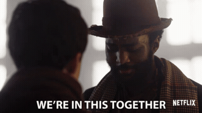 A Man Wearing A Hat And Scarf Talks To Another Man With The Words " We 'Re In This Together " Below Him GIF