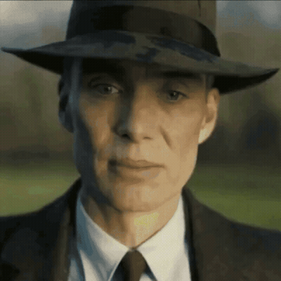 A Man Wearing A Hat And Suit Looks At The Camera GIF