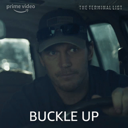A Man Wearing A Hat And Sunglasses Is Driving A Car With The Words " Buckle Up " On The Bottom GIF