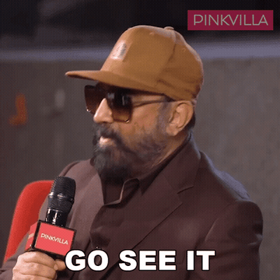 A Man Wearing A Hat And Sunglasses Is Holding A Microphone And Says Go See It GIF