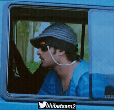 A Man Wearing A Hat And Sunglasses Is Looking Out Of A Car Window . GIF