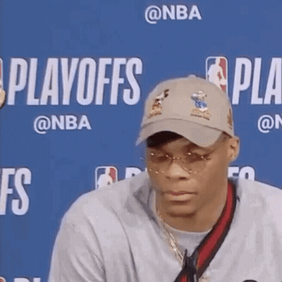 A Man Wearing A Hat And Sunglasses Is Sitting In Front Of A Blue Background With The Word Playoffs On It . GIF