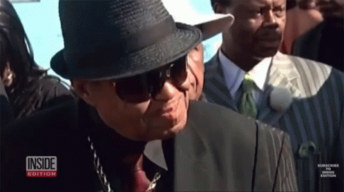 A Man Wearing A Hat And Sunglasses Is Standing In A Crowd With The Inside Edition Logo Visible GIF