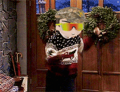A Man Wearing A Hat And Sunglasses Is Standing In Front Of A Door With A Wreath On It GIF
