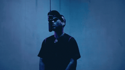A Man Wearing A Hat And Sunglasses Is Standing In Front Of A Microphone GIF