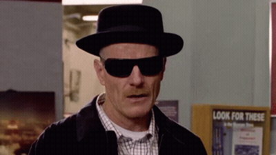 A Man Wearing A Hat And Sunglasses Is Standing In Front Of A Sign That Says `` Look For This '' . GIF