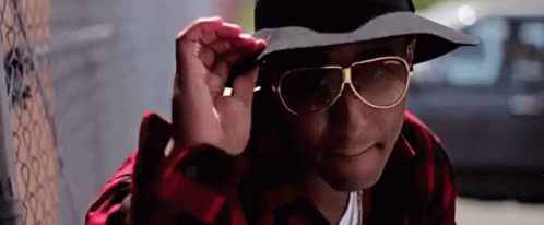 Man With Hat And Sunglasses Next To Fence GIF