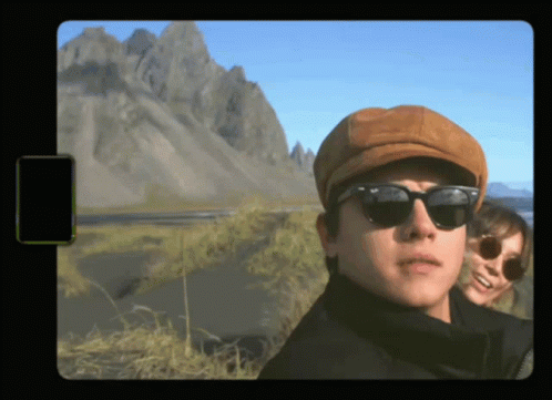 A Man Wearing A Hat And Sunglasses Stands Next To A Woman GIF