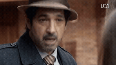 A Man Wearing A Hat And Tie Is Talking To Another Man GIF