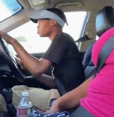 A Man Wearing A Hat And Visor Is Driving A Car Next To A Woman In A Pink Shirt GIF