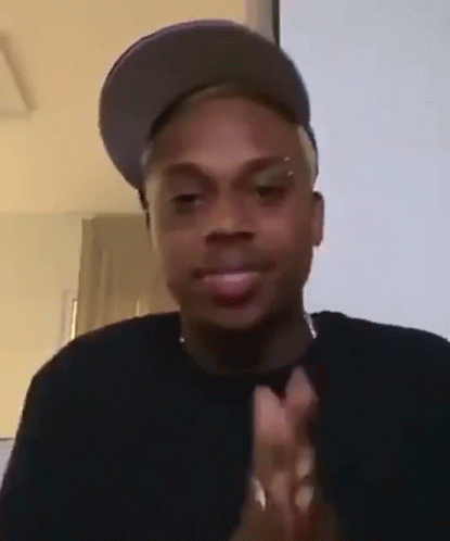 A Man Wearing A Hat Is Clapping His Hands . GIF