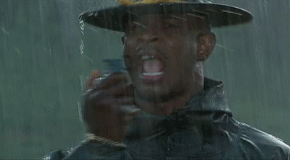 A Man Wearing A Hat Is Holding A Bottle Of Water In The Rain . GIF