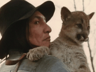 A Man Wearing A Hat Is Holding A Small Animal On His Shoulder GIF