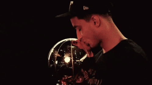 A Man Wearing A Hat Is Kissing A Trophy That Has The Letter N On It GIF