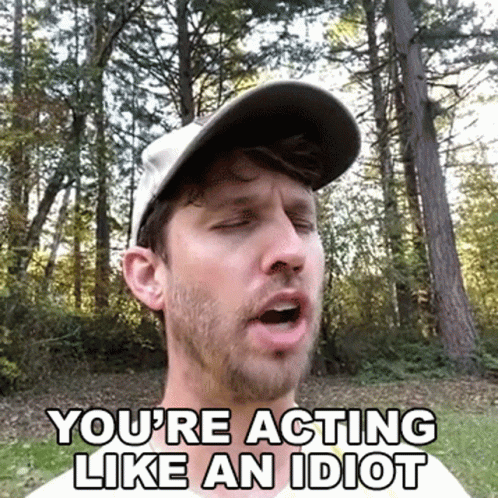 A Man Wearing A Hat Is Making A Funny Face While Standing In The Woods . GIF