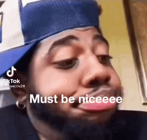 A Man Wearing A Hat Is Making A Funny Face With His Tongue Out . GIF