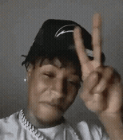 A Man Wearing A Hat Is Making A Peace Sign With His Hands . GIF