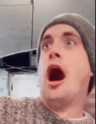 A Man Wearing A Hat Is Making A Surprised Face . GIF