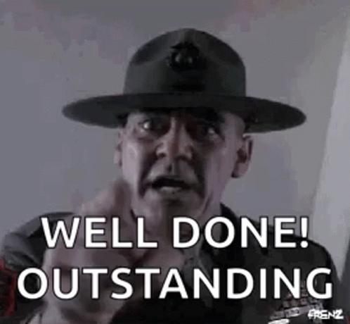 A Man Wearing A Hat Is Pointing At The Camera And Saying `` Well Done ! Outstanding '' . GIF