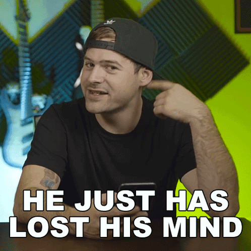 A Man Wearing A Hat Is Pointing To His Ear With The Words He Just Has Lost His Mind Behind Him GIF