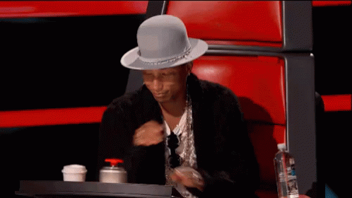 A Man Wearing A Hat Is Sitting In A Chair GIF
