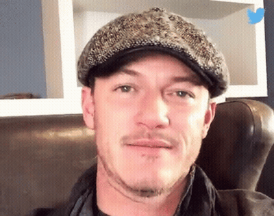 A Man Wearing A Hat Is Sitting On A Couch And Smiling GIF
