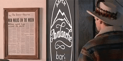 A Man Wearing A Hat Is Standing In Front Of A Sign That Says Avalanche Bar GIF