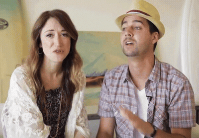 A Man Wearing A Hat Is Talking To A Woman Who Is Looking At Him GIF
