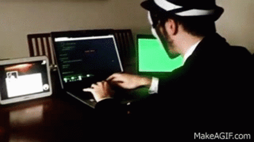 A Man Wearing A Hat Is Typing On A Laptop GIF