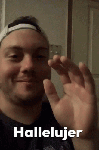 A Man Wearing A Hat Is Waving His Hand And The Words Hallelujer Are On The Bottom Of The Picture . GIF