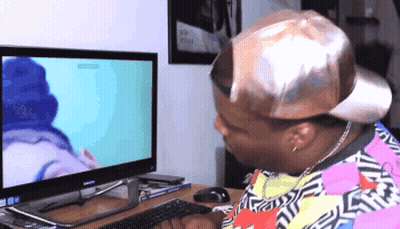 A Man Wearing A Hat Looks At A Computer Monitor GIF