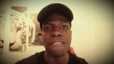 A Man Wearing A Hat Looks At The Camera With A Picture Of A Tiger In The Background GIF